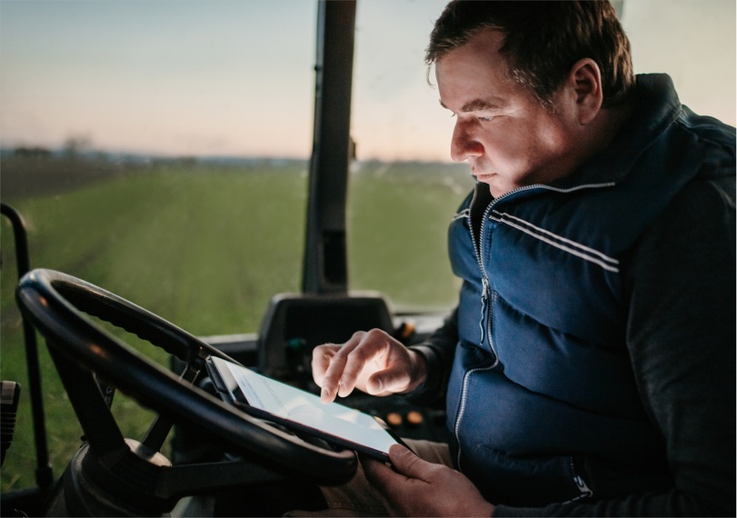 morotista de trator olhando um tablet dentro do trator